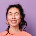 Happy asian girl making funny faces. Front view of trendy japanese young woman in earrings. Happy asian girl making funny faces. Front view of trendy japanese young woman in earrings.