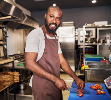 happy-young-chef-cutting-vegetables-in-restaurant-2023-11-27-05-25-08-utc