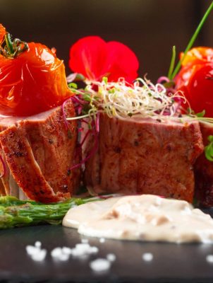 veal-medallions-with-asparagus-on-black-dishware-2025-02-25-01-07-32-utc