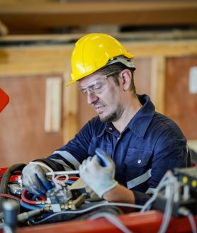 Robotic Arm engineer check on equipment in its with software of an Artificial Intelligence Processor Unit. Male technician programs a robot arm with a digital tablet and assembly robot in a factory. Apprentice engineers programming robots in factory.