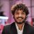 Smiling positive confident man in formal wear and headset sitting at office desk. Company worker with beard looking at camera. Concept of people and business.