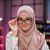 Smiling positive confident woman in formal wear and hijab and eyeglasses sitting at office desk. Company worker with headscarf looking at camera. Concept of people and business.