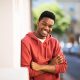 smiling young black man leaning against wall outside with arms crossed Portrait smiling young black man leaning against wall outside with arms crossed