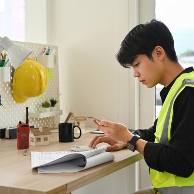 Young asian man working on the design of a construction plan or Young asian man working on the design of a construction plan or architecture model at the office.