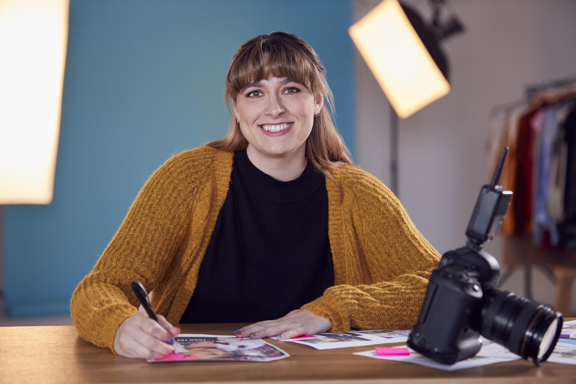 Portrait Of Female Photographer At Desk Checking Brief Before Fashion Shoot In Studio Portrait Of Female Photographer At Desk Checking Brief Before Fashion Shoot In Studio