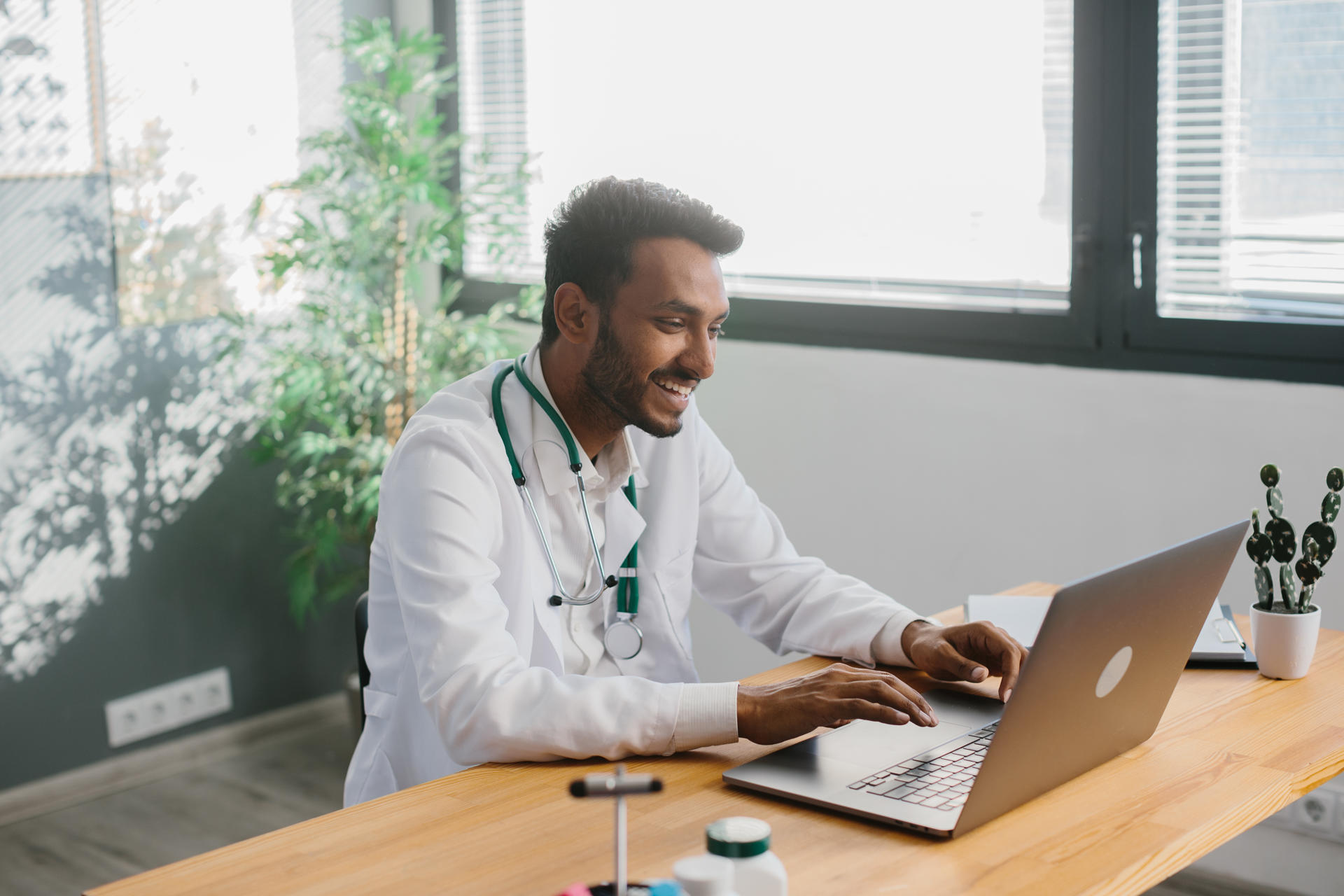 An Asian doctor uses a laptop to conduct an online consultation with a patient.