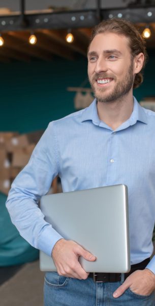 Smiling and conident man holding his computer Energetic man. A smiling and conident man holding his computer