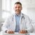 Portrait of happy middle aged male doctor having his own practice, physician in white lab coat uniform sitting in office Portrait of happy middle aged male doctor having his own practice, physician or cardiologist in white lab coat uniform sitting at desk in her modern office