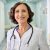 Smiling female happy doctor pediatrician standing in clinic hospital. Portrait. Portrait of smiling older senior female professional doctor physician pediatrician wearing white robe with stethoscope around neck standing in modern private clinic hospital looking at camera.