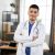 Smiling young 30-aged male Arabic Asian doctor posing with arms crossed in the office Smiling young 30-aged male Arabic Asian doctor posing with arms crossed in the office. Male physician in blue suit and white coat, with a stethoscope around neck, posing to camera indoors