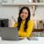 Smiling happy beautiful Asian woman relaxing using technology of Smiling happy beautiful Asian woman relaxing using technology of laptop computer. take note of information Have a relaxing hot drink while sitting on the table in your room at home.
