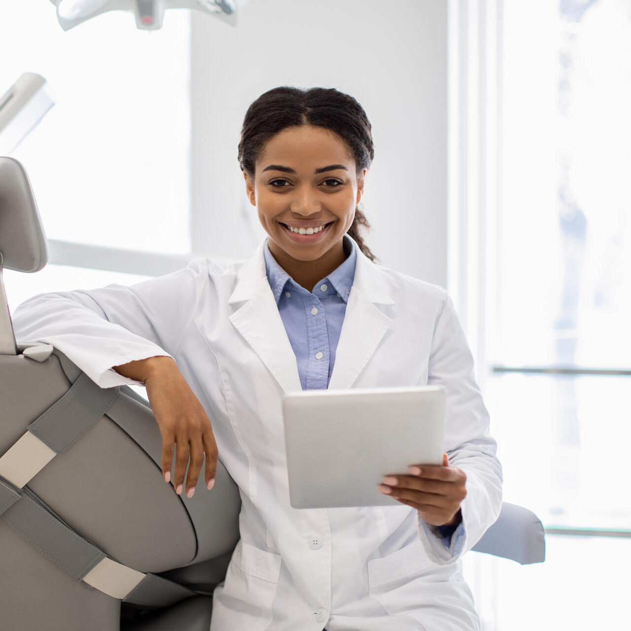 Happy Black Dentist Female With Digital Tablet Posing At Workplace In Clinic Happy Black Dentist Female With Digital Tablet Posing At Workplace In Clinic, Positive African American Doctor Waiting For Patient In Modern Stomatological Cabinet, Lookin And Smiling At Camera