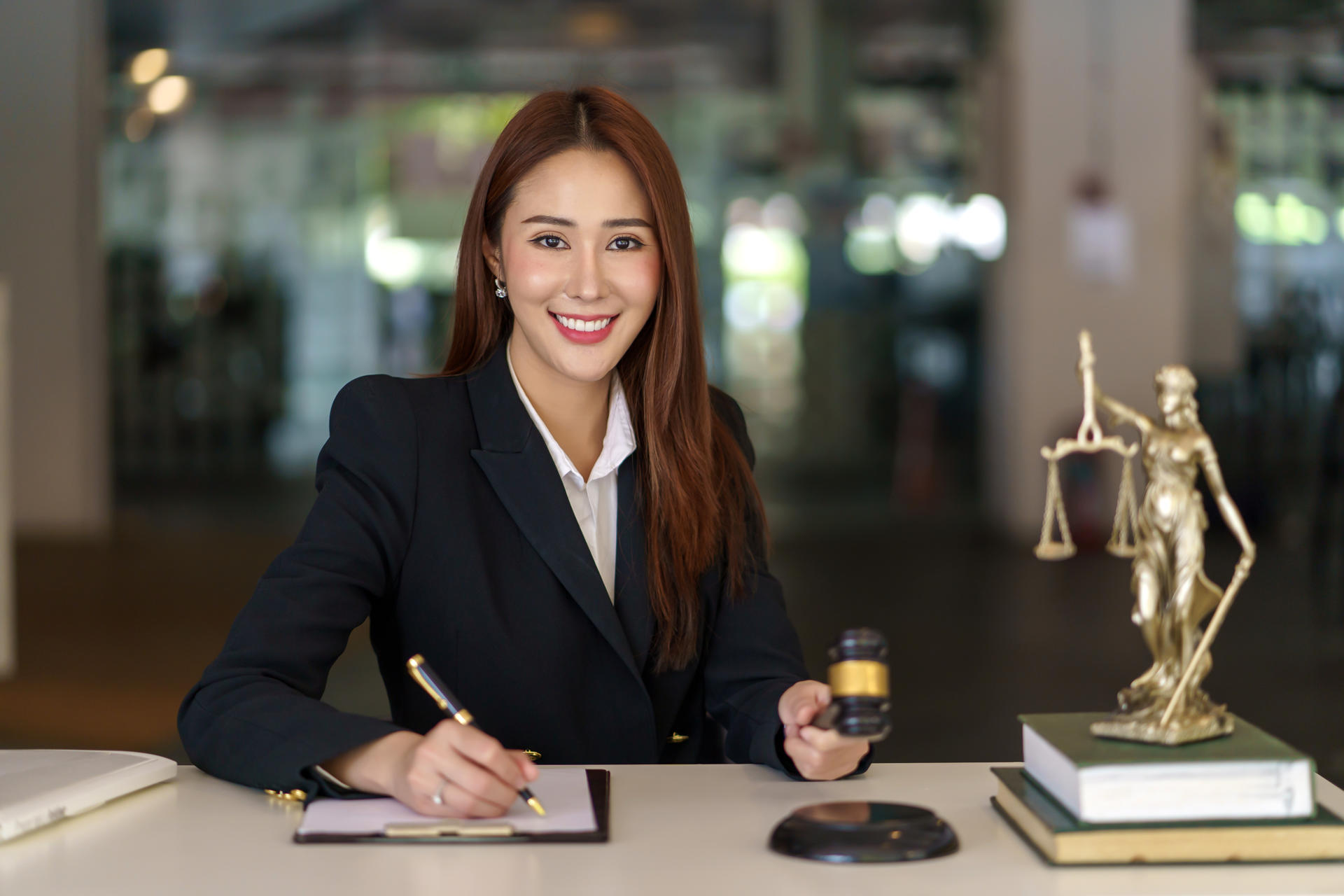 Beautiful young Asian lawyer woman with a smile sitting working at the office. Looking at camera.