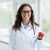 Beautiful young european woman dietologist wearing eyeglasses holding apple Beautiful young european woman dietologist wearing eyeglasses holding apple in her hand, recommending fresh fruits for healthy diet, nutrition, posing next to window at clinic, copy space