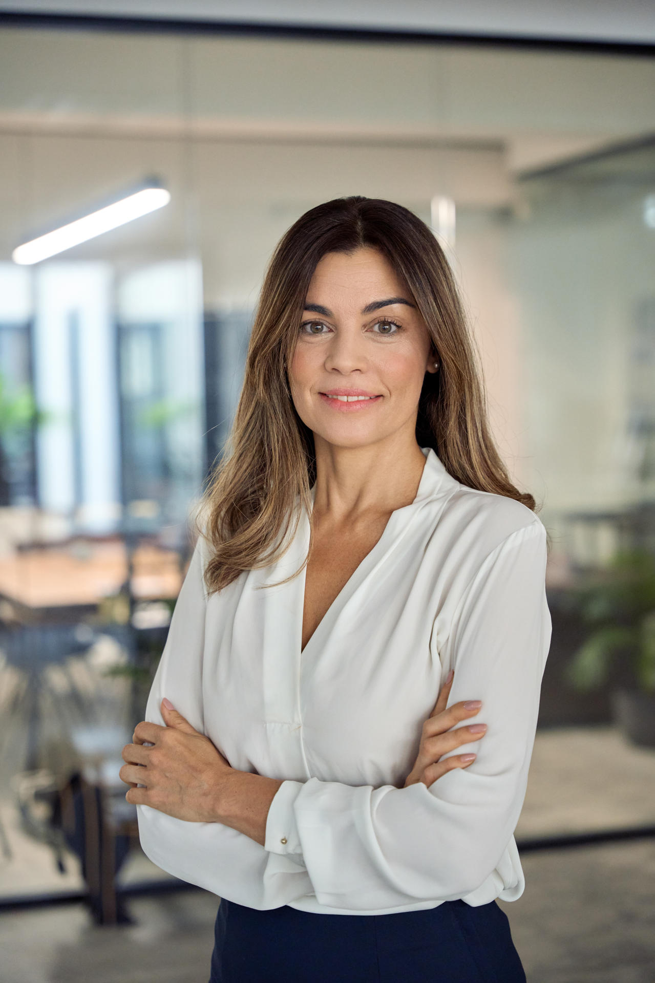 Smiling confident Latin professional mature business woman in office, portrait. Smiling confident Latin professional mid aged business woman in 40s, corporate leader, happy mature female executive, lady manager standing in office arms crossed looking at camera, vertical portrait.