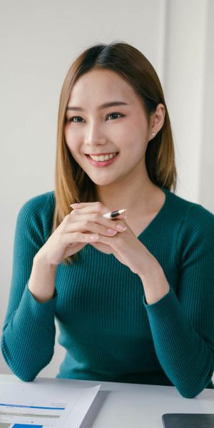A woman in a green sweater sits at a desk with a man A woman in a green sweater sits at a desk with a man. She is smiling and she is happy