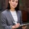 Young confident Asian business woman entrepreneur holding tablet, portrait. Young confident elegant professional leader Asian business woman, female executive manager consultant, entrepreneur wearing suit holding tablet standing outside office looking at camera, vertical.